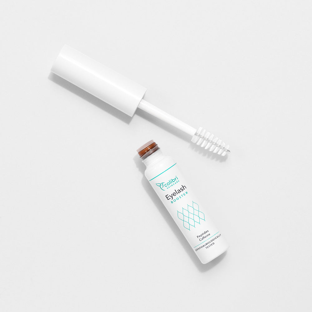 Weiße Tube eines Wimpernserums mit geöffnetem Deckel auf einem weißen Hintergrund.