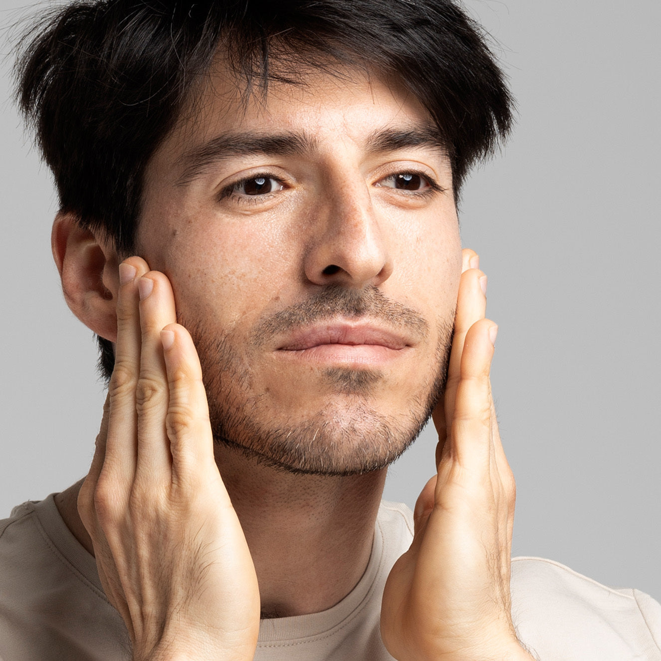 Ein Mann berührt mit seinen Händen seine Wangen und schaut nachdenklich in die Ferne.