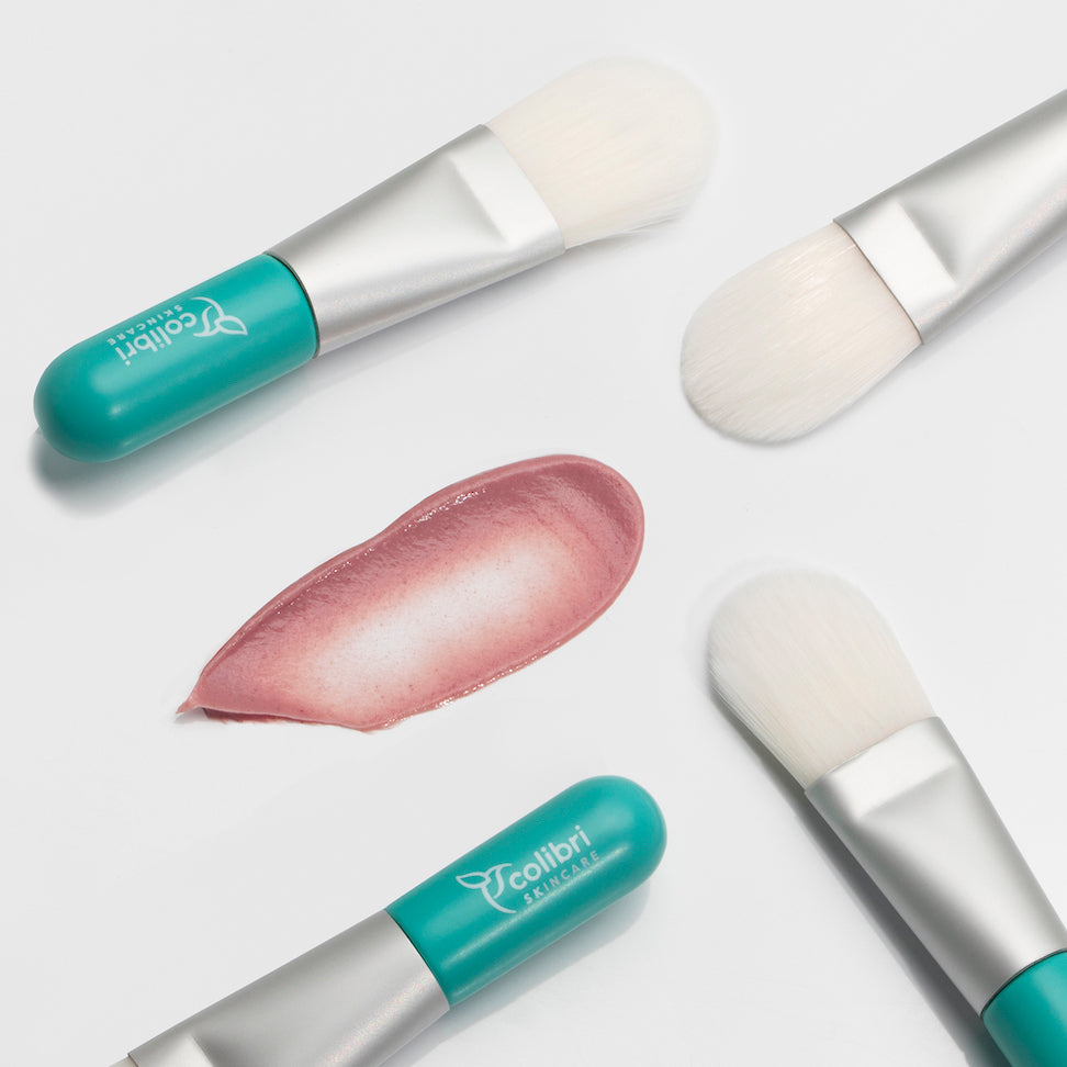 Make-up-Pinsel mit grünem Griff und rosa Creme auf weißem Hintergrund.