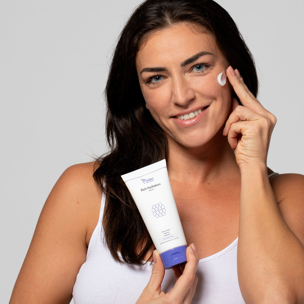 Frau trägt eine Feuchtigkeitscreme auf das Gesicht auf und hält die Tube 'Rich Hydration' in der Hand.