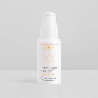 Weiße Flasche Sonnencreme mit der Aufschrift "Ultra Light SPF 50+" vor grauem Hintergrund.