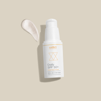 Flasche einer Daily SPF 50+ Sonnencreme von Colibri Skincare neben einem Klecks der Creme auf beigem Hintergrund.